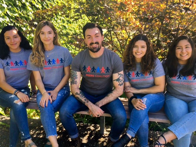 Image of four students sitting and smiling at the camera